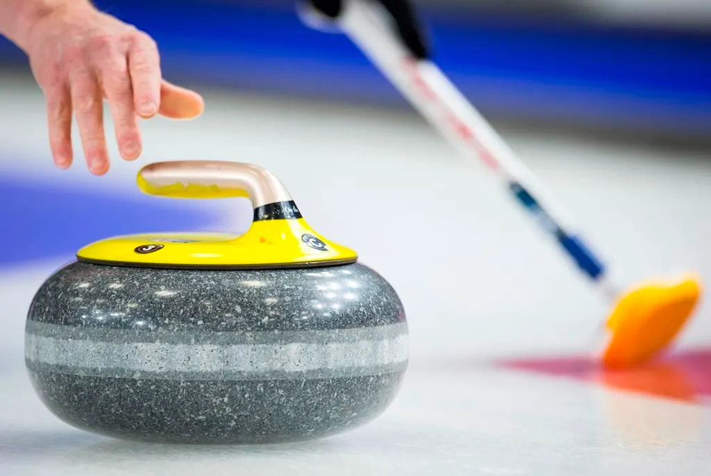 A hand throwing a curling rock.
